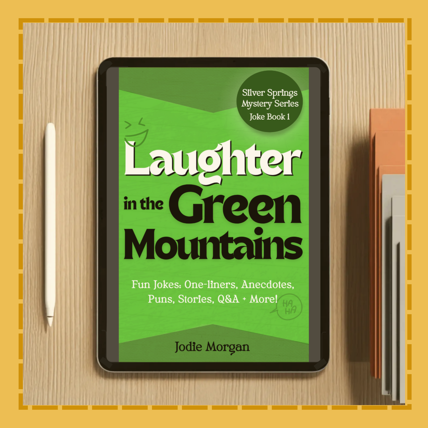 Ebook cover of 'Laughter in the Green Mountains' on a digital device with a pen and book on a wooden surface.