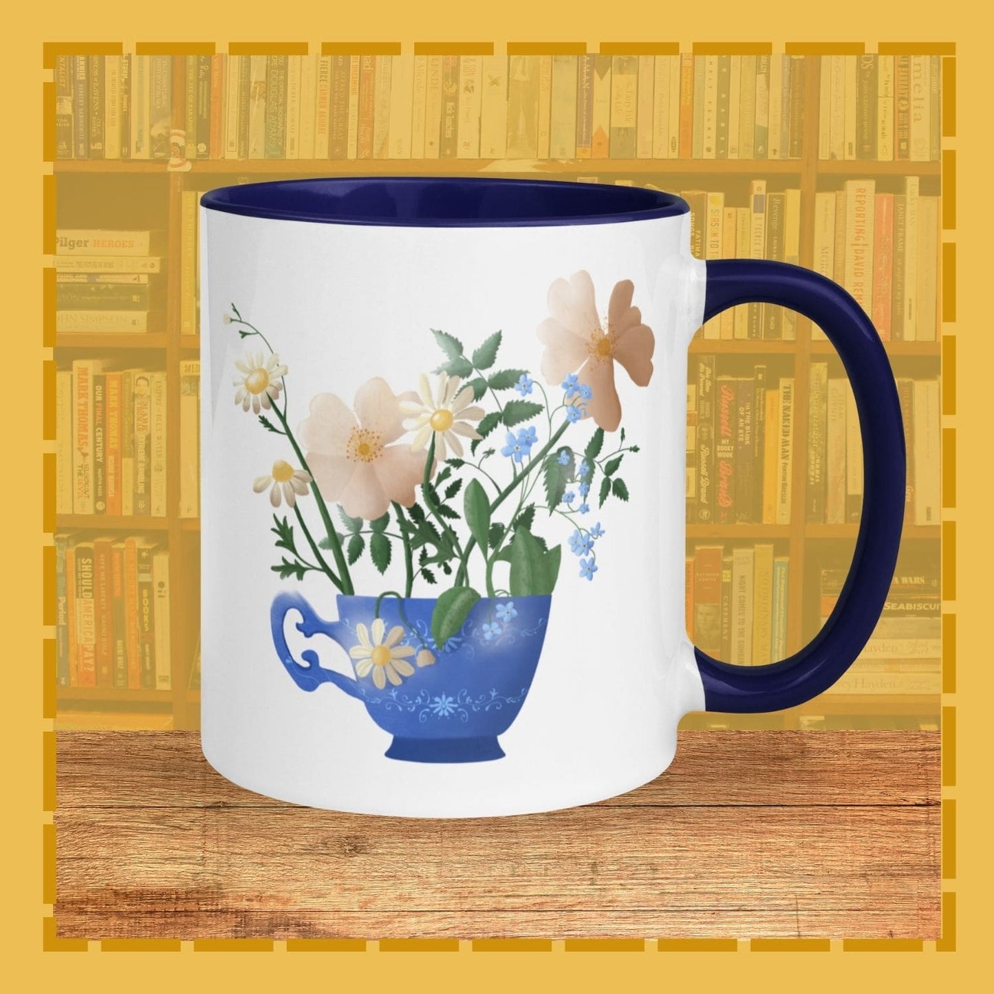 Mug with floral design and blue handle on a wooden surface with bookshelf background