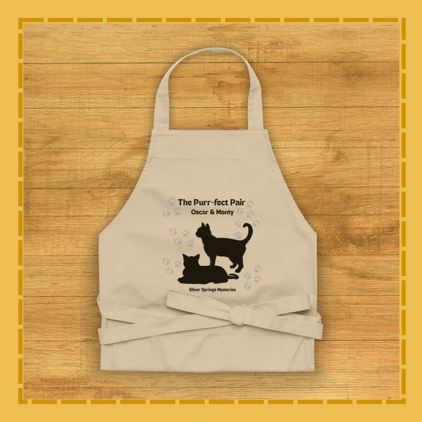 Beige apron with cat design and text on a wooden surface