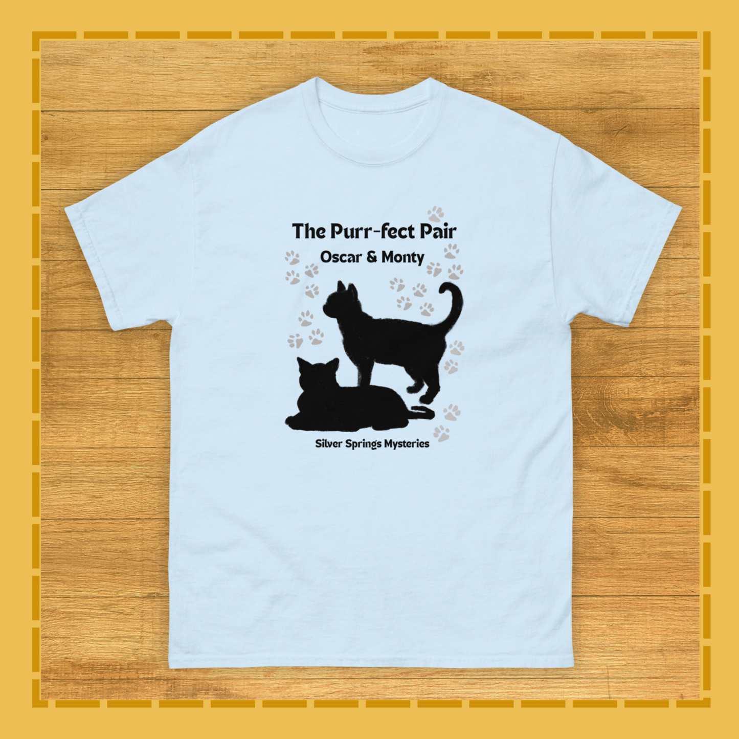 Light blue t-shirt with black cat silhouette design on a wooden surface