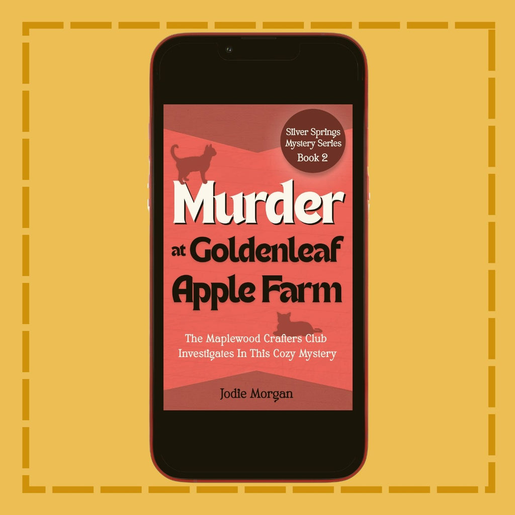 Phone displaying the book cover of 'Murder at Goldenleaf Apple Farm' on a yellow background