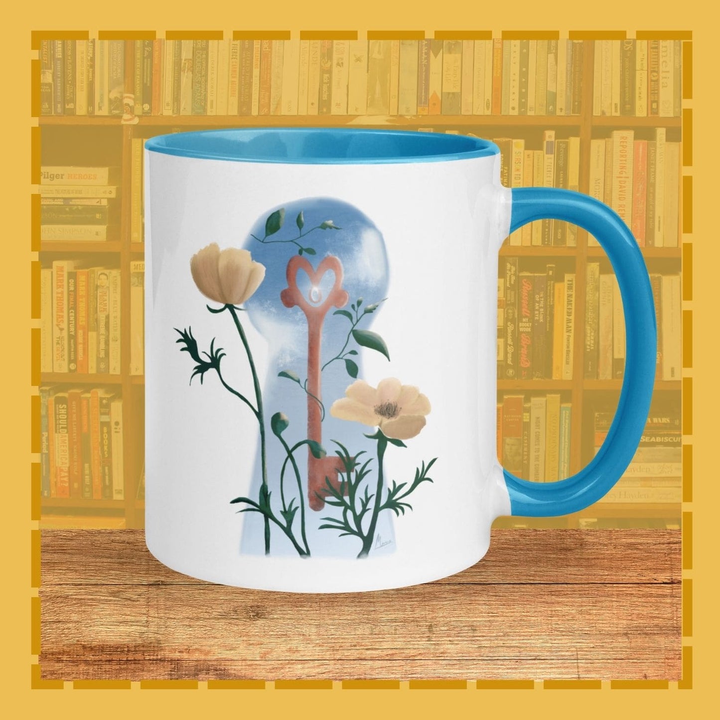 Mug with floral design and blue handle on a wooden surface with bookshelf background