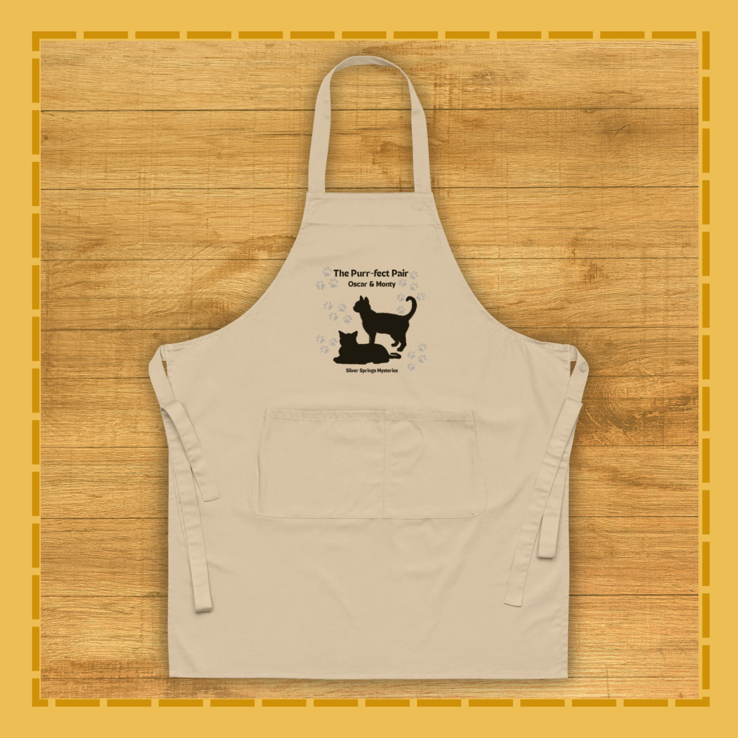 Beige apron with black cat and dog design on a wooden surface