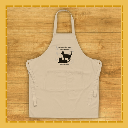 Beige apron with black cat and dog design on a wooden surface