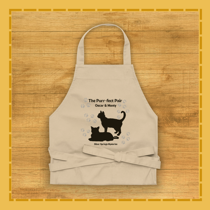Beige apron with cat design and text on a wooden surface