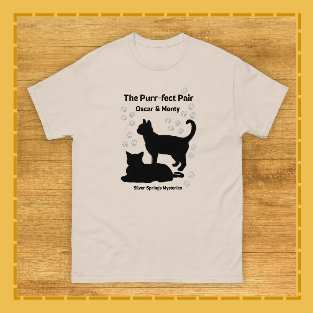 Beige t-shirt with black cat design and text on a wooden surface